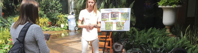 Reiman Gardens intern leading a youth tour with children sitting on the ground
