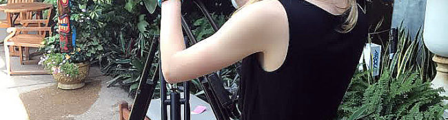 botanical garden intern standing in the tropical plant conservatory with a video camera recording footage
