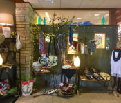 indoors at a botanicl garden outside a gift shop with items for sale like clothes, purses, lamps and more.