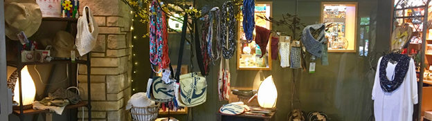 indoors at a botanicl garden outside a gift shop with items for sale like clothes, purses, lamps and more.