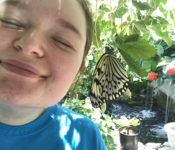 intern smiling with a black and white butterfly nearby