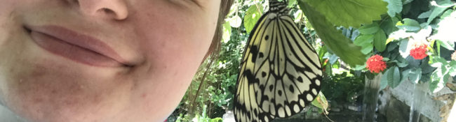 intern smiling with a black and white butterfly nearby