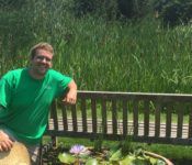 Reiman Gardens intern sitting outside on a bench in front of lake helen