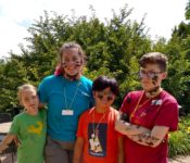 Youth education program with three smiling students covered in mud posing with a tearcher