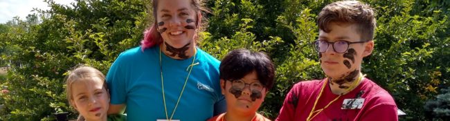 Youth education program with three smiling students covered in mud posing with a tearcher