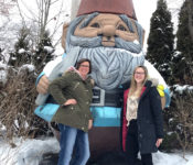 two interns pose witth Elwood the Worlds Tallest Concrete gnome in winter