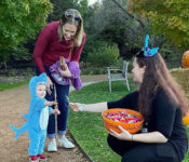 volunteer passing out candy during Reiman Gardens Halloween event with a child in a costume