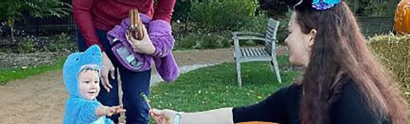 volunteer passing out candy during Reiman Gardens Halloween event with a child in a costume
