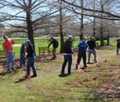 group of volunteers raking outdoors in the early spring in bald cypress allee