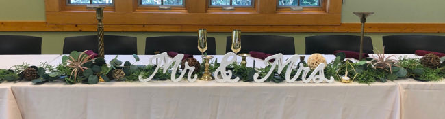 indoors in a rental space setup for a wedding with plants, candleabras, chamaign glasse