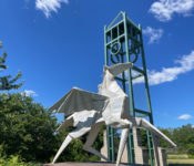 outdoors during spring with a large metal white origami sculpture and a campanile