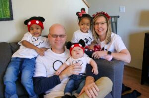 woman and man sitting with three young children wearing Mickey Mouse ears